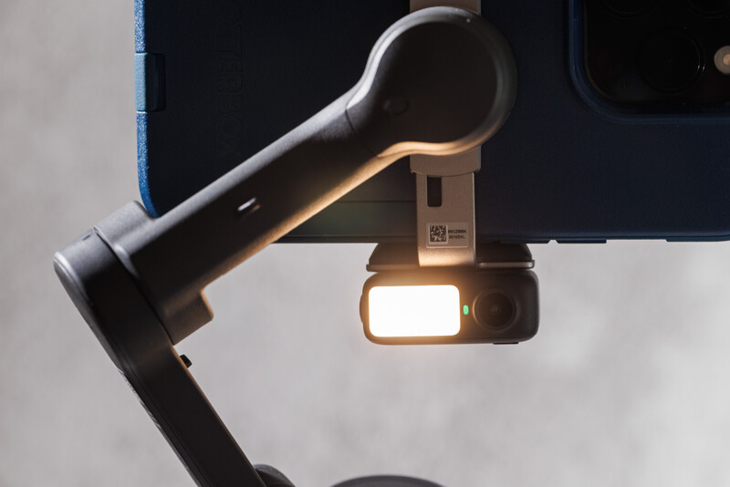 Professional camera rig with mounted microphone and LED light panel against white background.