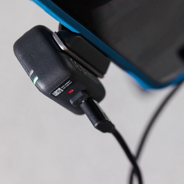 Black wireless microphone receiver with attached cable and indicator lights.