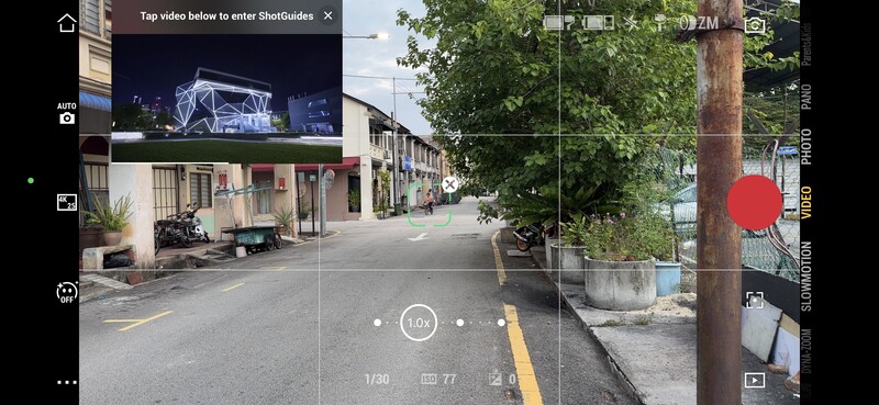 Screenshot of a mobile camera app interface showing a street scene with buildings and a utility pole.
