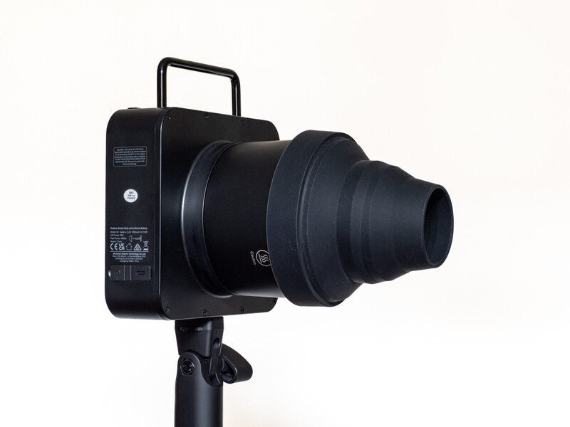 Black cinema camera mounted on tripod with telephoto lens attached.