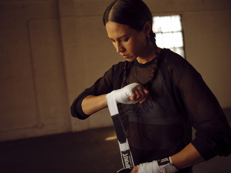 Athlete wrapping hand with white boxing tape before training or competition.