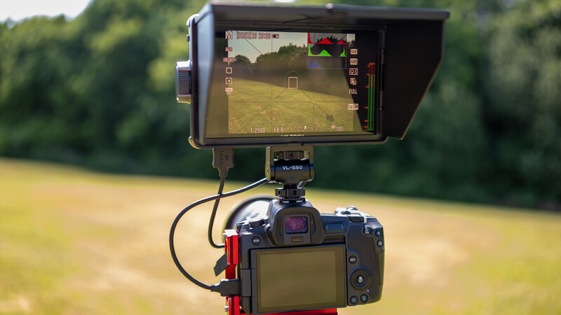 DSLR camera with external monitor mounted on top displaying live video feed of a soccer field.