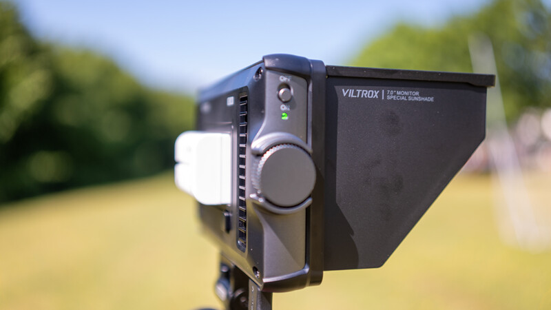 Viltrox LED light fixture mounted on a stand outdoors with natural green landscape background.