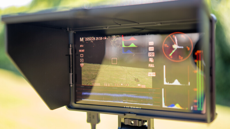 Video monitor displaying camera viewfinder interface with waveform, histogram, and timecode overlays.