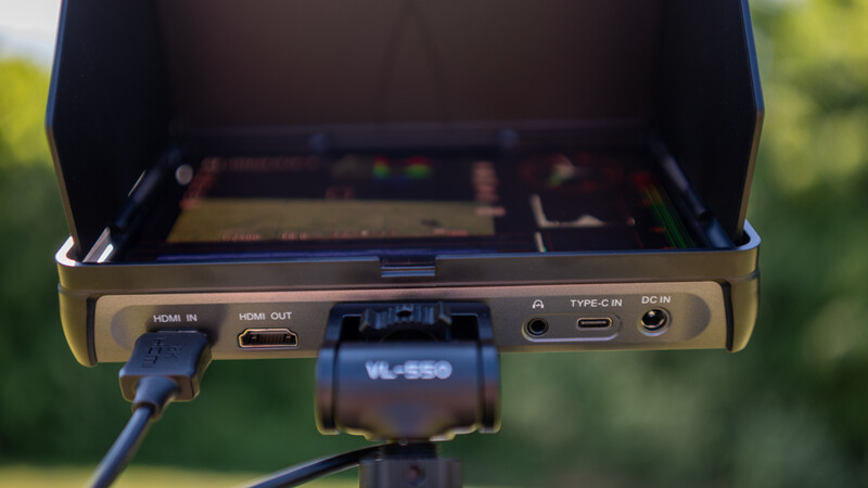 Rear panel of portable monitor showing HDMI ports, USB-C connection, and power input against blurred green background.