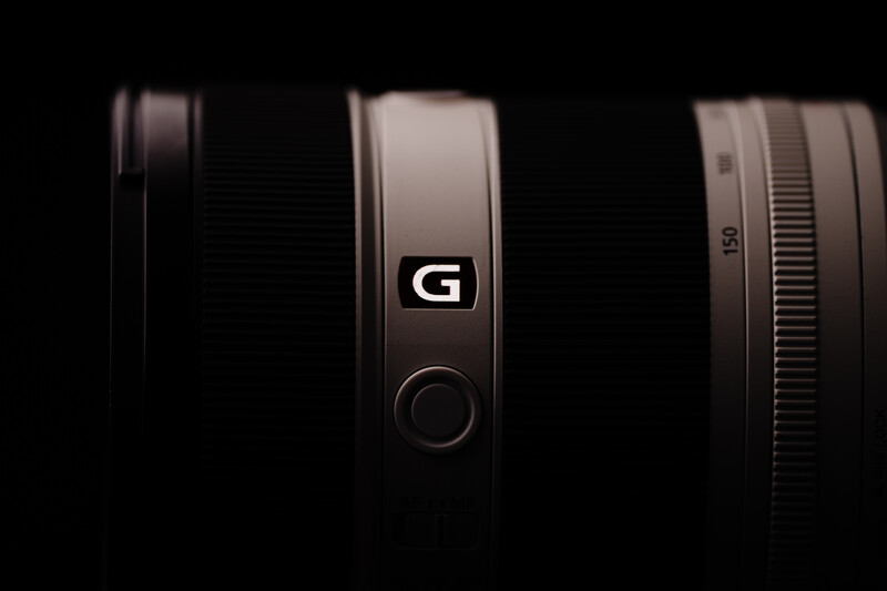 Three camera lenses arranged against a black background, with the center lens displaying a prominent G logo.