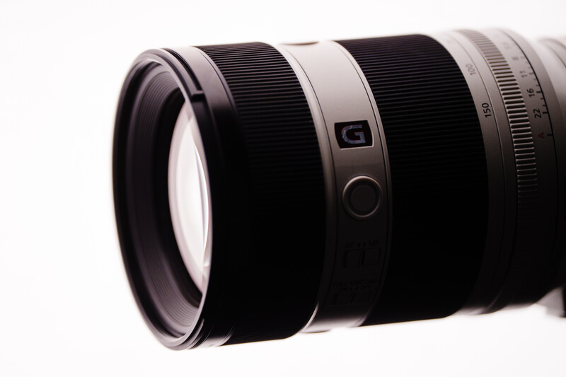 Close-up of a telephoto zoom lens with white and black barrel segments against a white background.