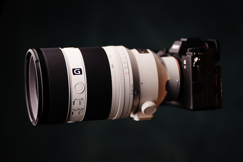 Sony G-series telephoto lens mounted on mirrorless camera body against dark background.