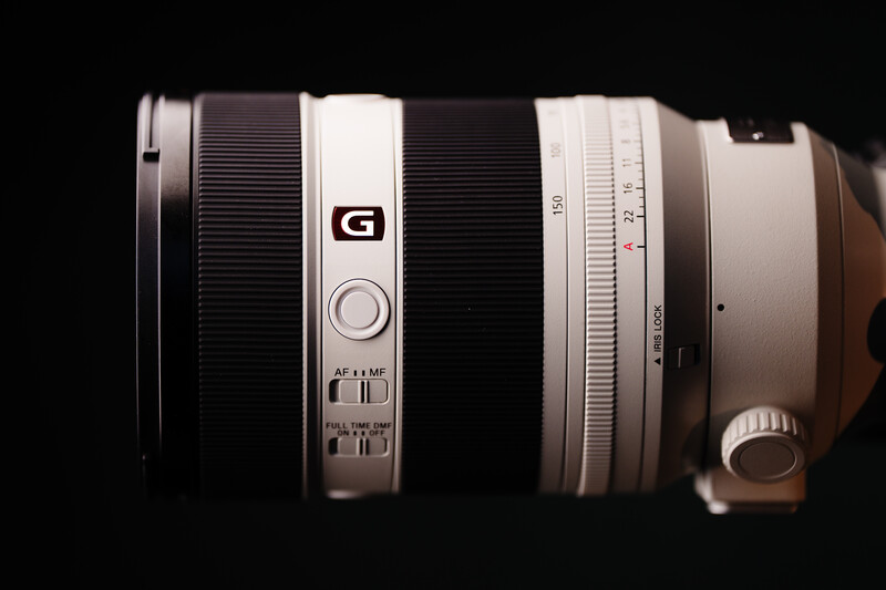 Sony G-series telephoto zoom lens with white and black barrel segments against dark background.