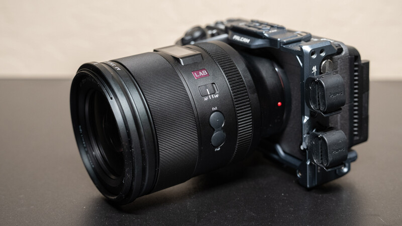 Black mirrorless camera with attached prime lens on gray surface.
