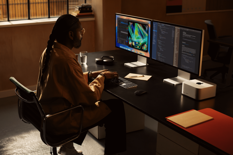 Creative professional working at a dual-monitor setup displaying colorful design work.