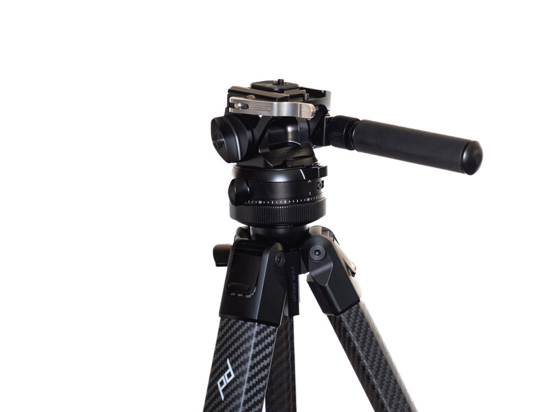 Professional tripod with fluid video head and carbon fiber legs against white background.