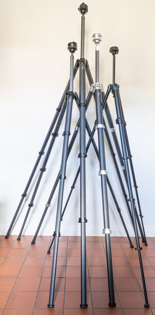 Multiple light stands arranged in a tipi-like formation on a terracotta floor.