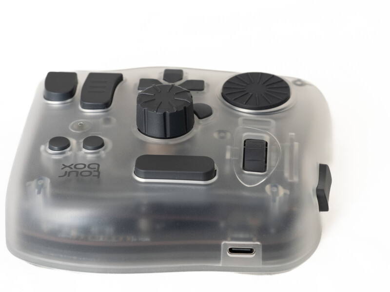 Translucent camera controller with black buttons and dial controls visible through clear plastic housing.