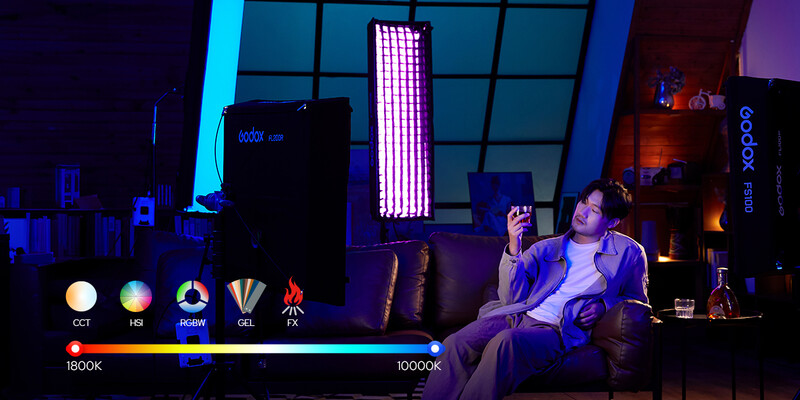 Studio setup with two people seated on a couch under purple and blue gel lighting with color temperature scale display.