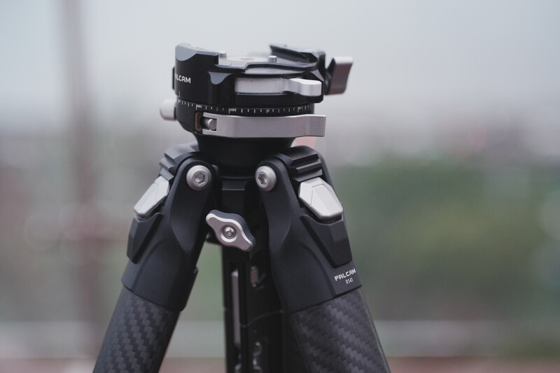 Professional tripod head with pan-tilt mechanism and fluid damping system mounted on carbon fiber legs.