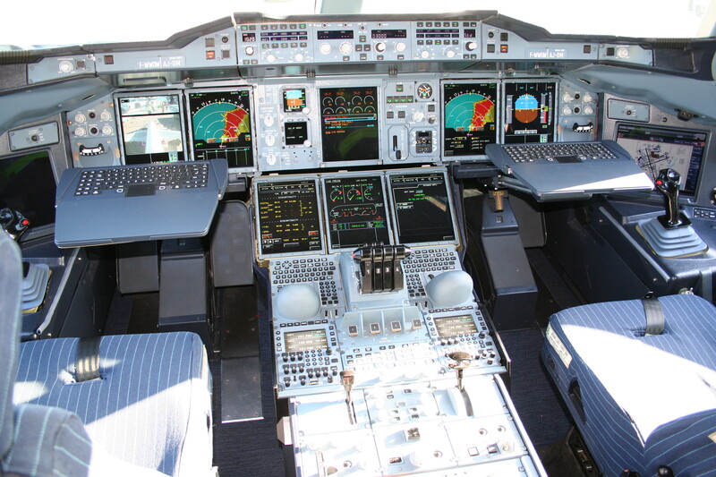 Aircraft cockpit with multiple displays, control panels, and instrumentation throughout the overhead and center console areas.