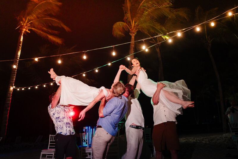 Group of people lifting a person above their shoulders during an outdoor evening celebration.