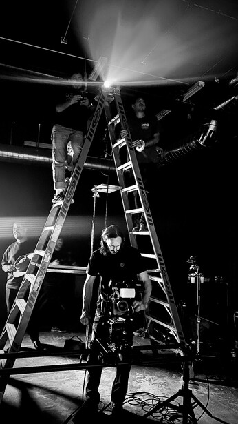 Musician performing on stage under dramatic overhead lighting during a concert setup.