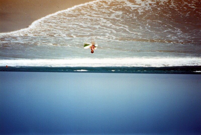Child holding a surfboard standing in the ocean waves near the shoreline.