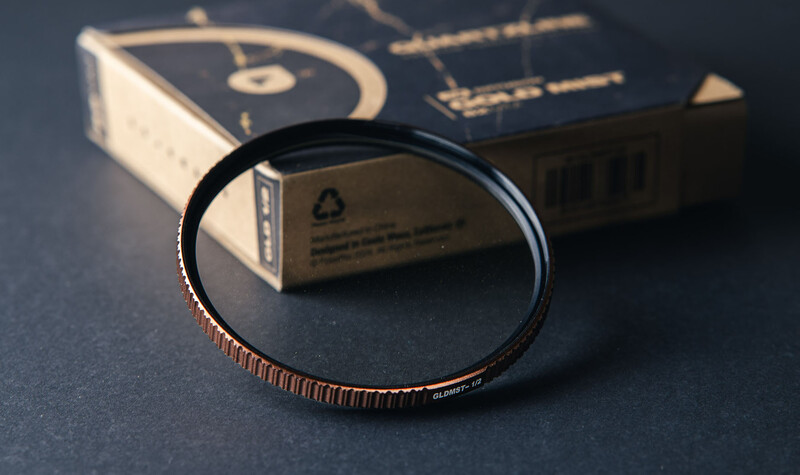 Copper-textured camera filter ring displayed next to its product packaging on dark surface.