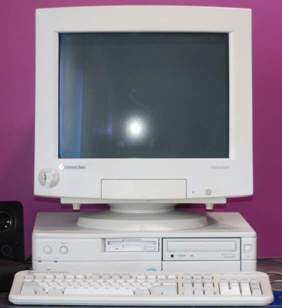 Vintage computer setup with CRT monitor, beige tower, and keyboard against bright magenta wall.