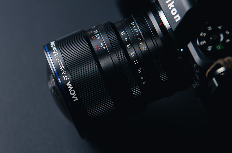 Laowa prime lens mounted on camera body against dark background.