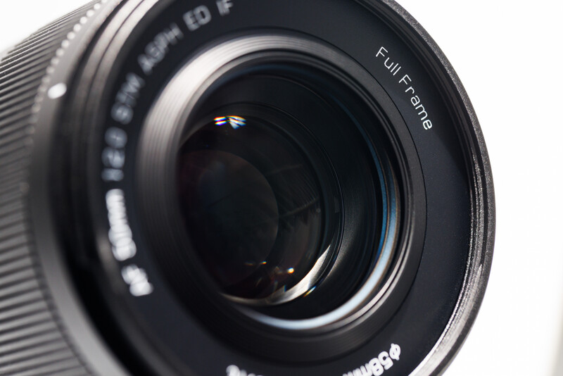 Close-up of a camera lens showing the front element and focusing ring with text markings.