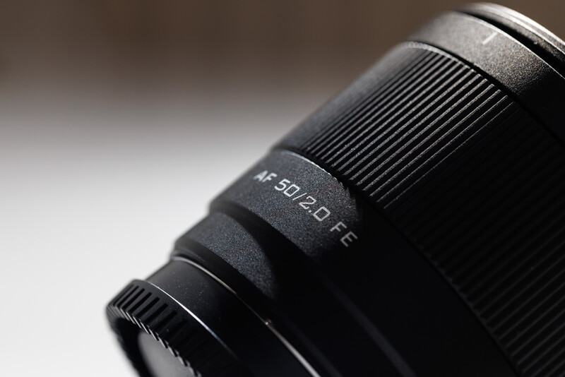 Close-up detail of a telephoto lens barrel showing focal length markings and ribbed rubber grip zone.