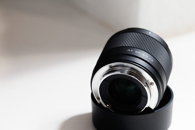 Camera lens with black rubber grip and metal bayonet mount on white background.