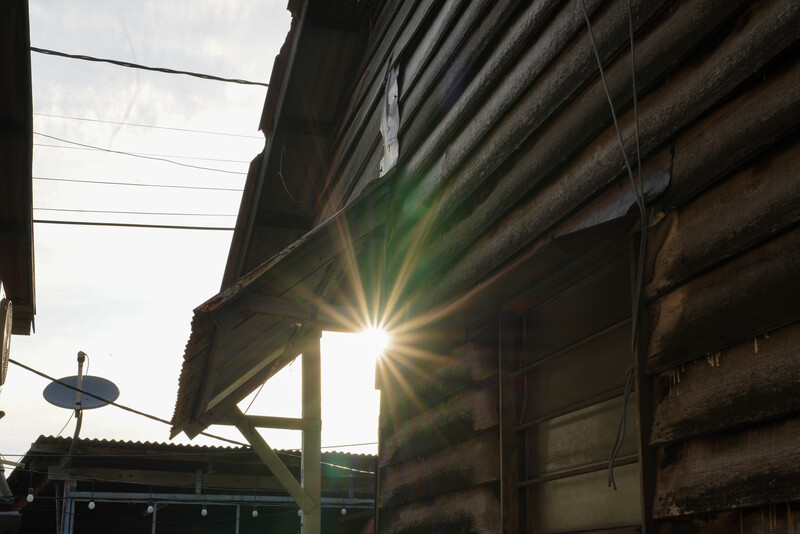 Bright sunlight streaming through a gap between industrial corrugated metal structures.