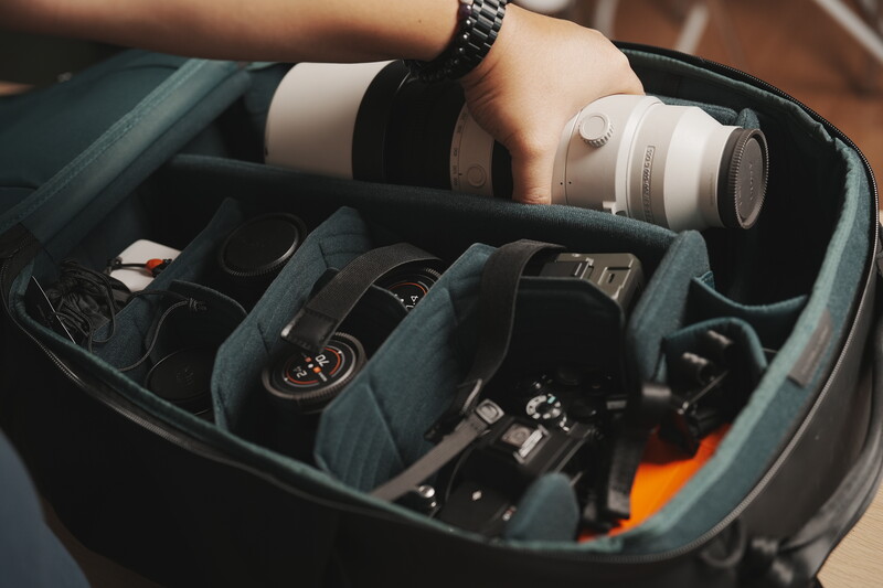 Camera bag interior displaying organized photography gear including lenses, camera body, and accessories in padded compartments.