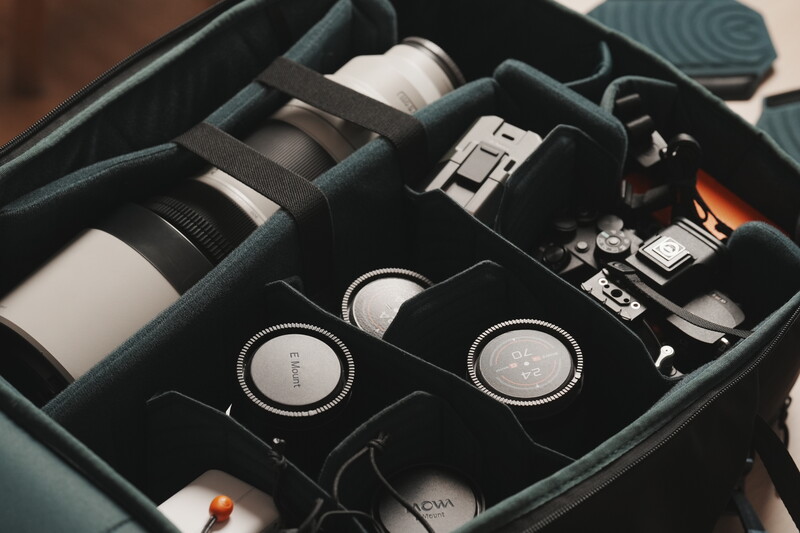 Organized camera gear bag with lenses, camera body, and accessories neatly arranged in foam compartments.