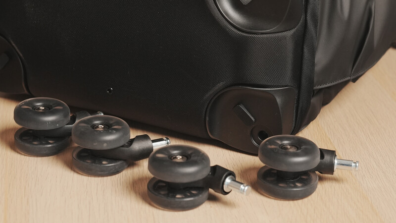 Black camera lens weights and pouches arranged on a wooden surface next to a black camera bag.