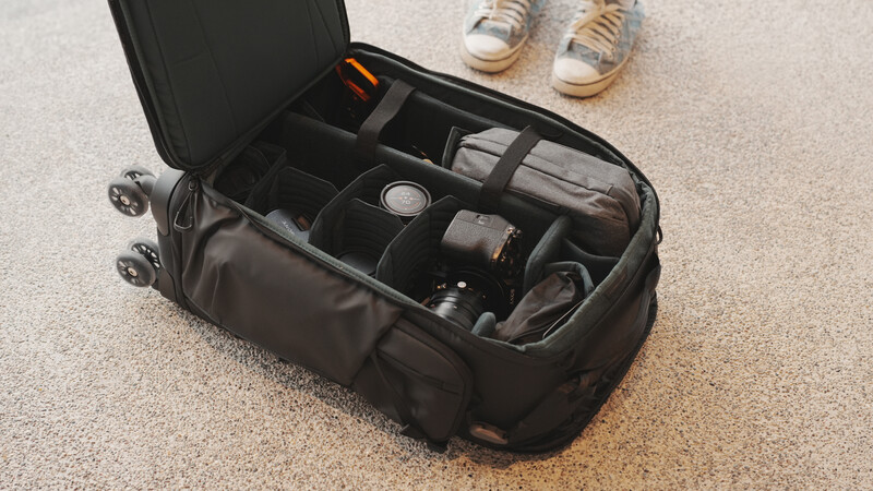 Open camera gear travel case with padded dividers holding photography equipment and accessories.