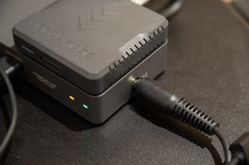 Compact wireless router with attached external antenna on dark surface.
