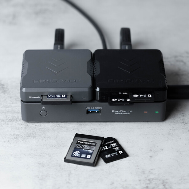 Two wireless microphone transmitters with antennas and two SD memory cards on a concrete surface.