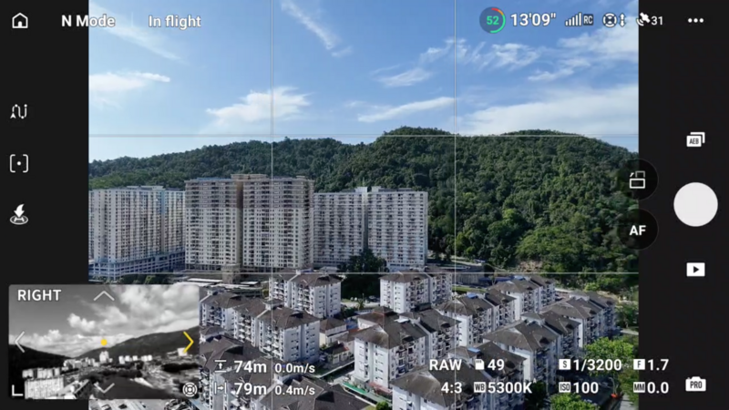 Aerial drone footage showing apartment buildings with forested hills in the background.