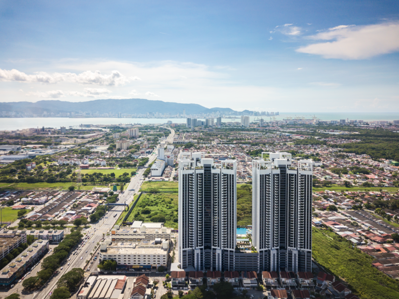 Aerial view of twin residential towers overlooking a sprawling suburban landscape with mountains in the distance.