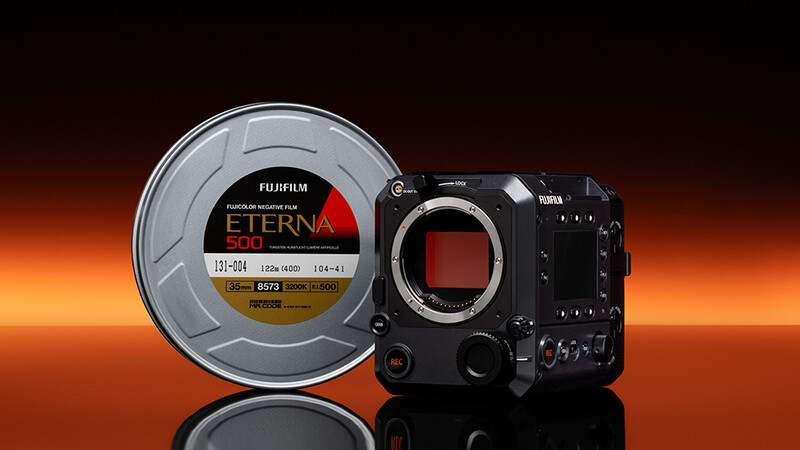 Fujifilm Eterna 500 film canister displayed beside a black cinema camera body against an orange gradient background.