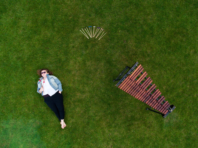 Aerial view of a man lying on grass next to a striped blanket and picnic items.