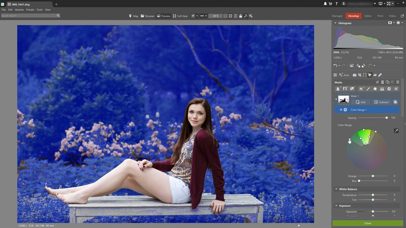 Woman in burgundy cardigan seated on bench against vivid blue floral backdrop.