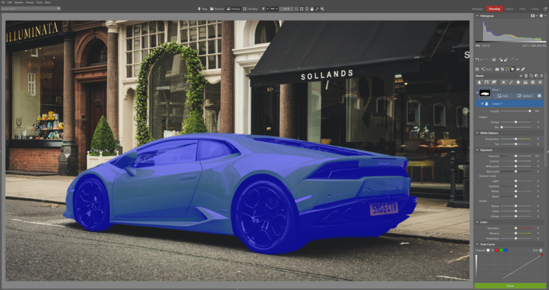 Bright blue sports car parked on a street in front of luxury storefronts with ivy-covered facades.