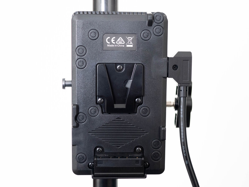 Rear view of a professional camera power distribution device with V-mount battery plate and cable connections.