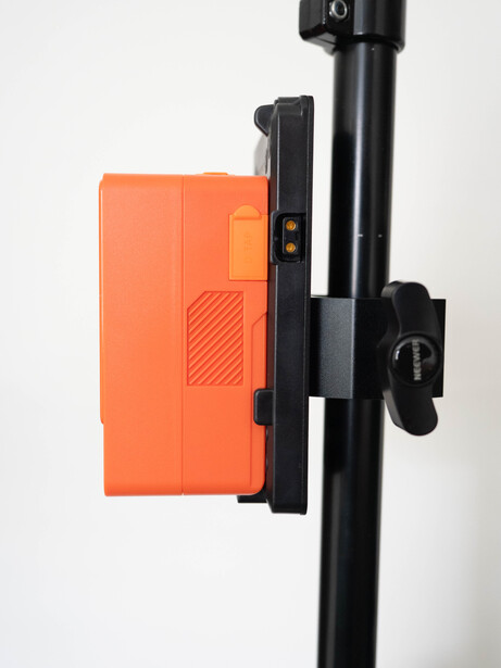 Orange mounting bracket attached to black vertical pole with adjustment clamps.