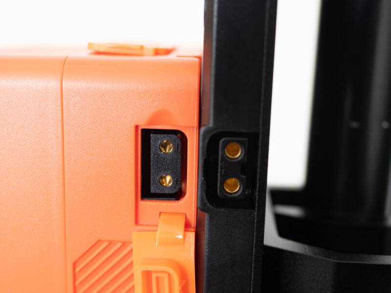 Close-up of orange and black camera or equipment connectors with gold-plated contact pins.