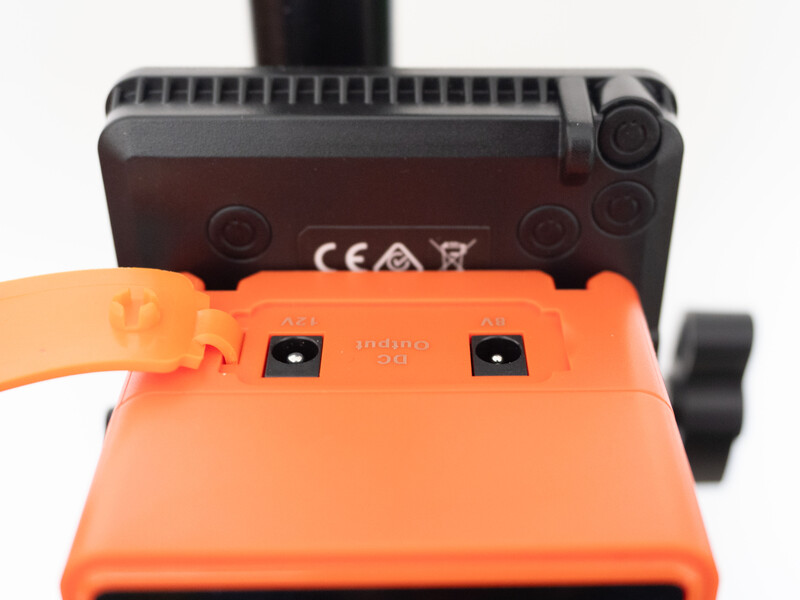 Bottom view of a wireless controller with orange battery cover removed, revealing battery compartment contacts.