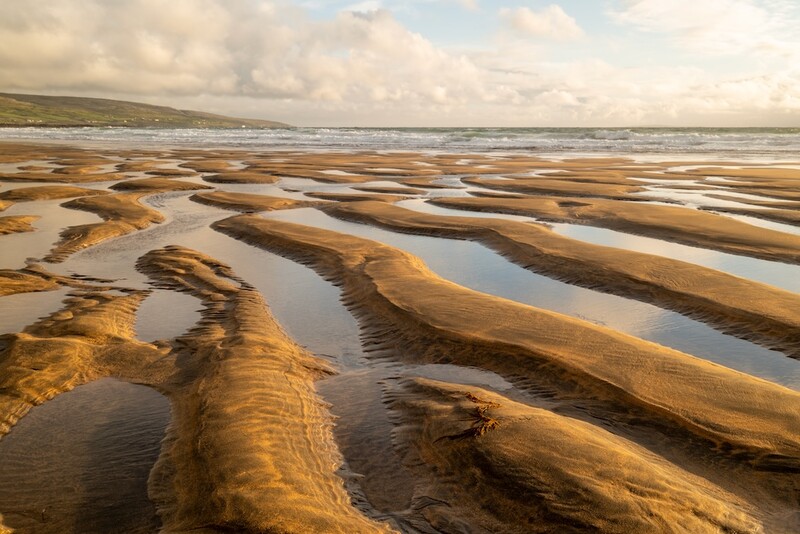 Tidal flats with parallel sand ridges and shallow water channels at low tide.