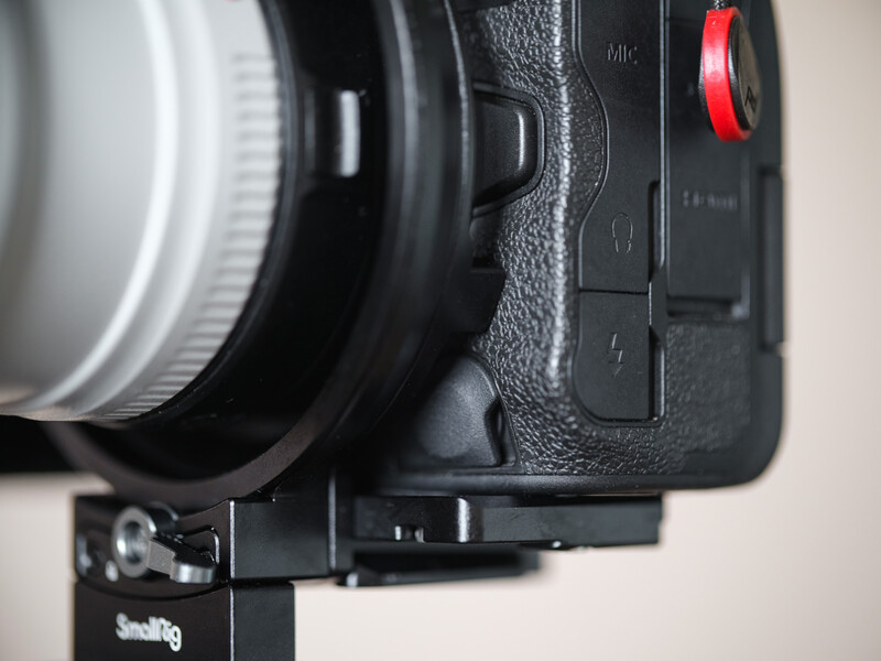 Close-up side view of a camera body with lens mounted and red record button visible.