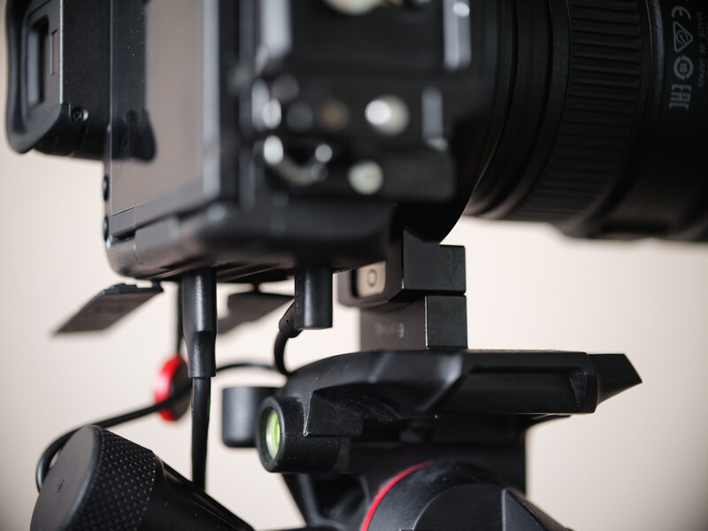Close-up of a professional camera rig with flash and mounting bracket on tripod head.